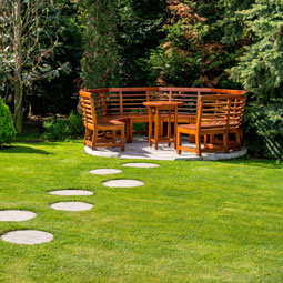 wooden benches in a synthetic lawn with property managers guide to save money on landscaping using artificial grass